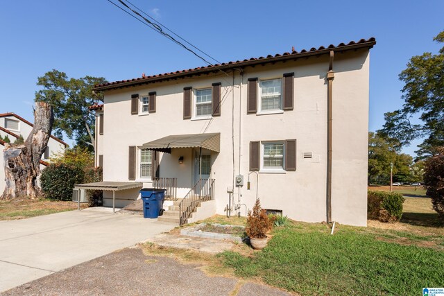 mediterranean / spanish-style house with a front yard and a carport