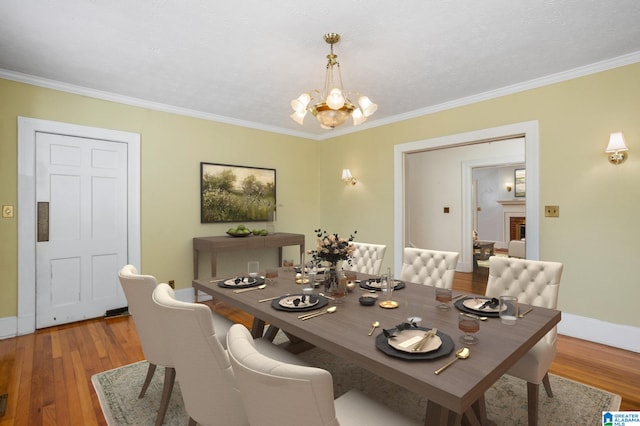 dining room with crown molding, hardwood / wood-style floors, and an inviting chandelier