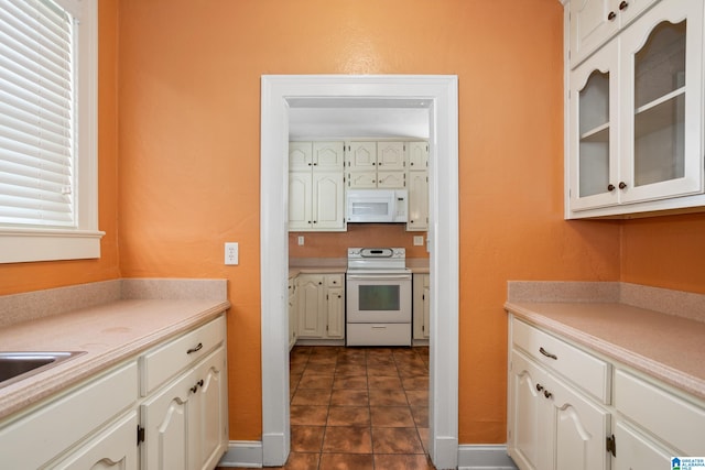 kitchen featuring white cabinetry, white appliances, and dark tile patterned flooring