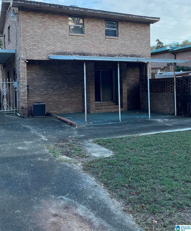 rear view of house with central air condition unit and a yard