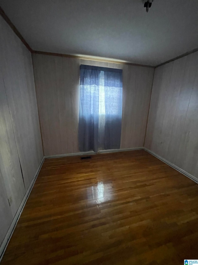 unfurnished room with wood walls and dark hardwood / wood-style flooring