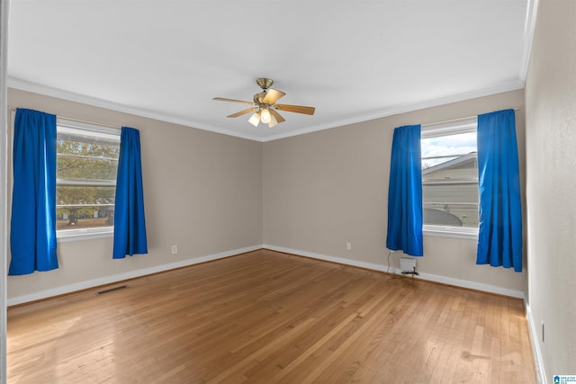 empty room featuring a wealth of natural light, ornamental molding, hardwood / wood-style flooring, and ceiling fan