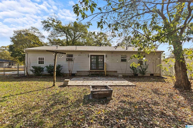 back of property with a yard, an outdoor fire pit, and a patio