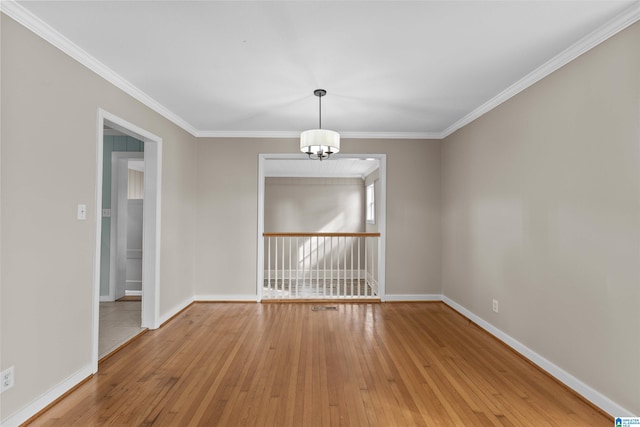 empty room featuring a notable chandelier, ornamental molding, and hardwood / wood-style floors