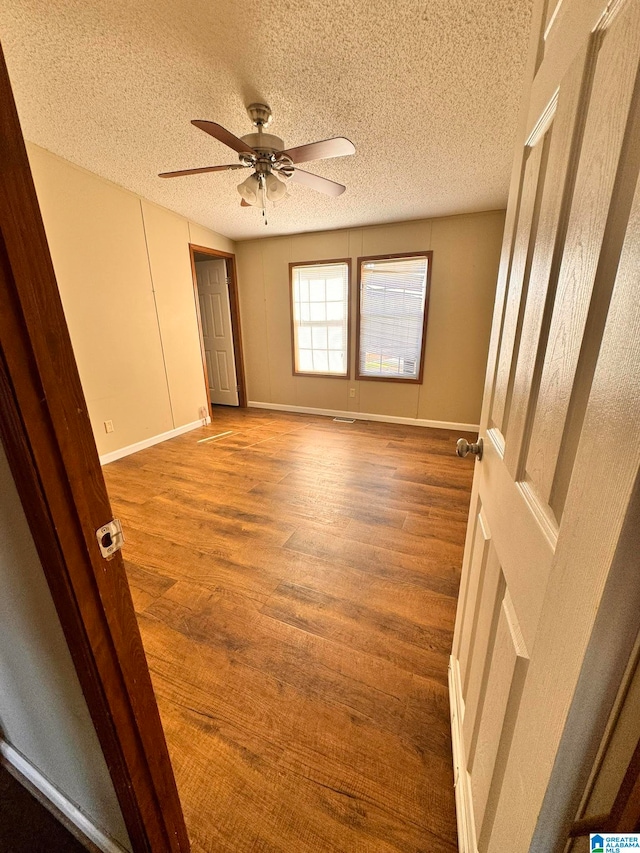 unfurnished bedroom featuring ceiling fan, hardwood / wood-style flooring, and a textured ceiling