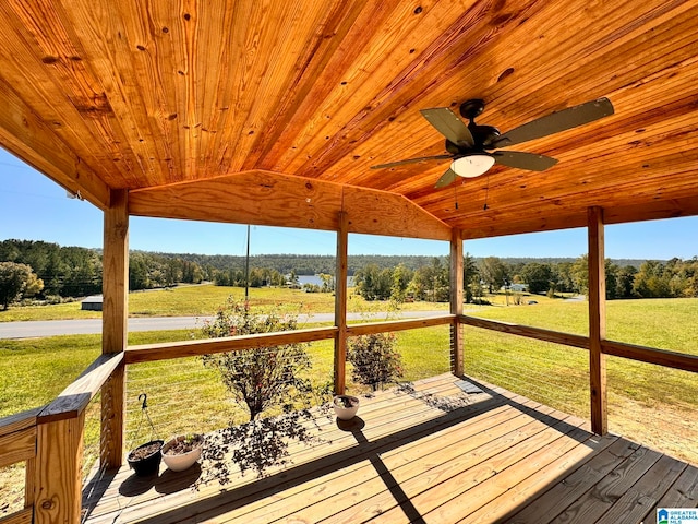 wooden terrace featuring ceiling fan, a lawn, and a rural view