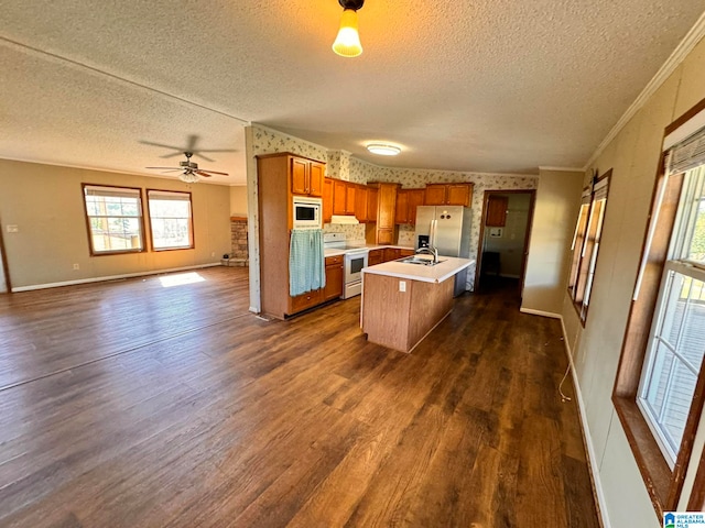 kitchen featuring a textured ceiling, white appliances, dark wood-type flooring, and an island with sink