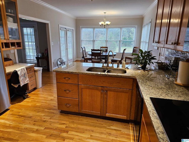 kitchen featuring black electric cooktop, ornamental molding, sink, an inviting chandelier, and light wood-type flooring