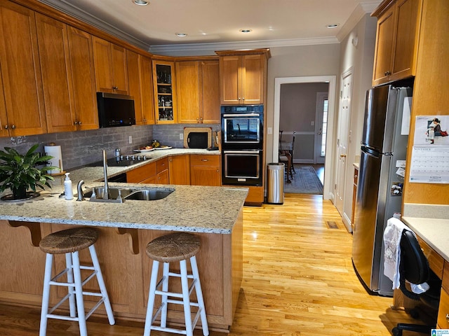 kitchen with backsplash, light stone countertops, stainless steel refrigerator, light hardwood / wood-style floors, and crown molding