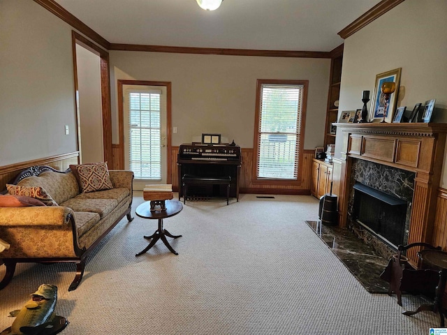 carpeted living room featuring a premium fireplace, crown molding, and wooden walls