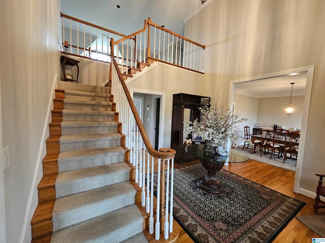 staircase with hardwood / wood-style floors, a high ceiling, and crown molding