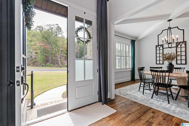 interior space with beamed ceiling, a wealth of natural light, hardwood / wood-style flooring, and a notable chandelier