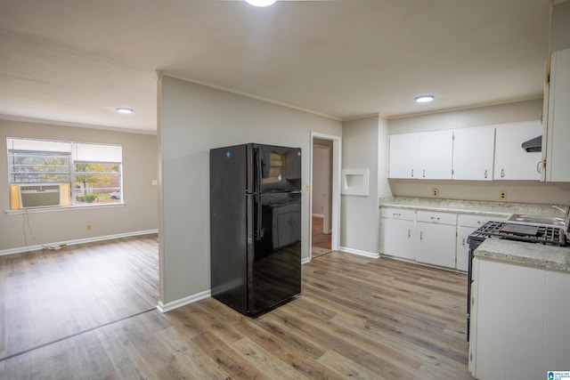 kitchen featuring white cabinets, light hardwood / wood-style flooring, black fridge, and gas range gas stove