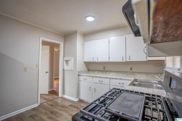 kitchen featuring white cabinets, light hardwood / wood-style floors, ornamental molding, and sink