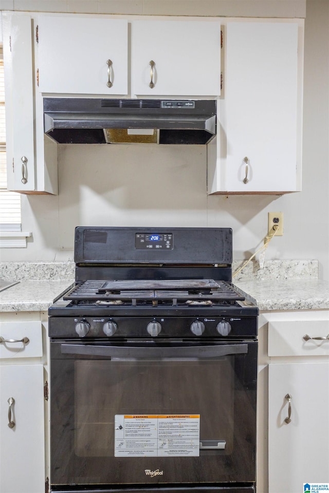 kitchen with black gas stove and white cabinetry