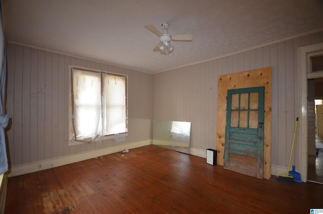 unfurnished living room featuring wood walls, ornamental molding, and dark hardwood / wood-style flooring