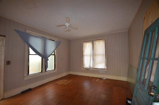 spare room with crown molding, hardwood / wood-style floors, and wood walls