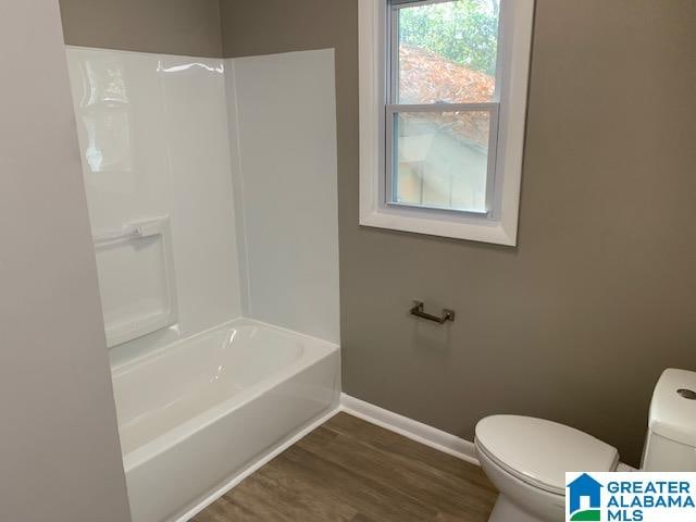 bathroom featuring toilet, wood-type flooring, and shower / washtub combination