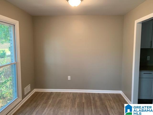 spare room with dark hardwood / wood-style flooring and plenty of natural light