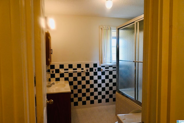 bathroom with vanity, an enclosed shower, tile patterned floors, and tile walls