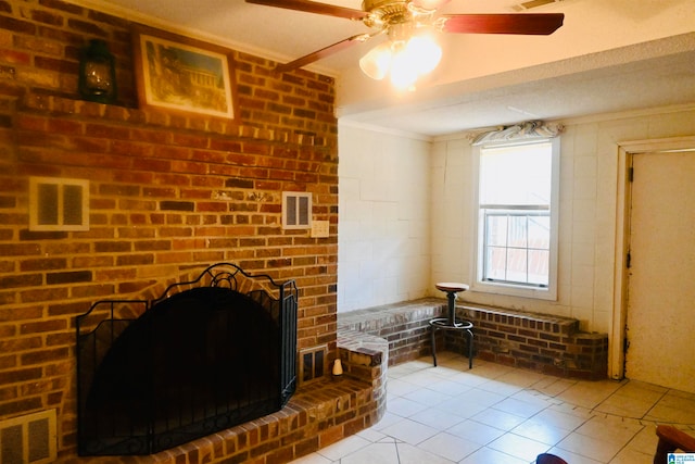 living room with ceiling fan, crown molding, light tile patterned floors, and a brick fireplace