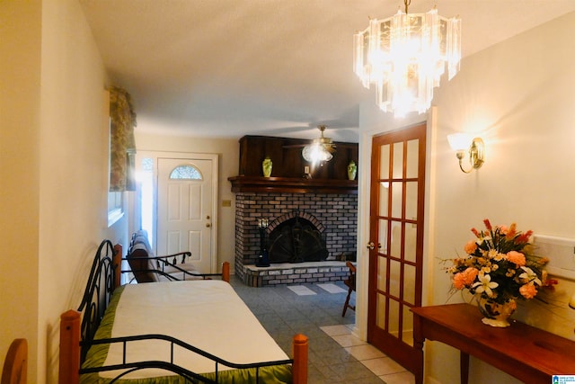 tiled living room featuring a brick fireplace and ceiling fan with notable chandelier