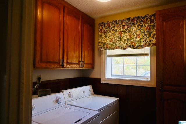 washroom featuring cabinets, a textured ceiling, wooden walls, and washer and clothes dryer