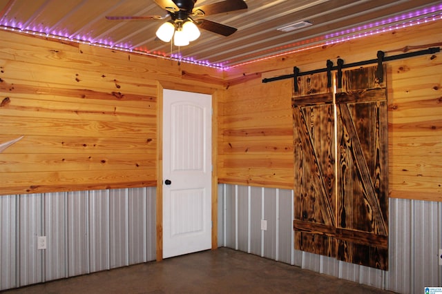 empty room with ceiling fan, wood ceiling, and wood walls