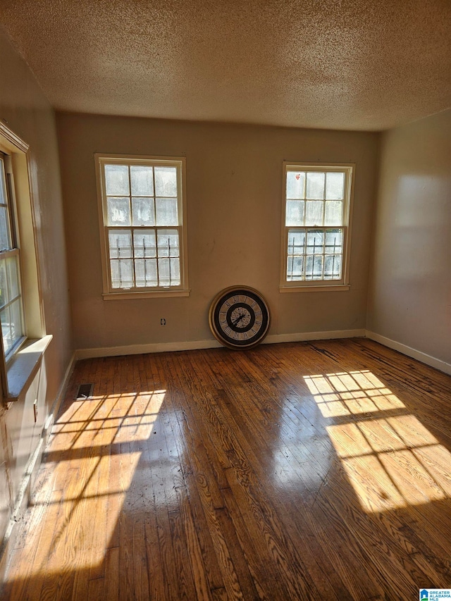 empty room with wood-type flooring and a textured ceiling