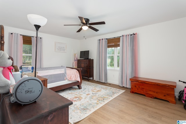 bedroom featuring ceiling fan, multiple windows, and light wood-type flooring