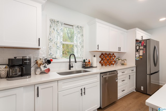 kitchen featuring backsplash, white cabinetry, light hardwood / wood-style flooring, sink, and stainless steel appliances