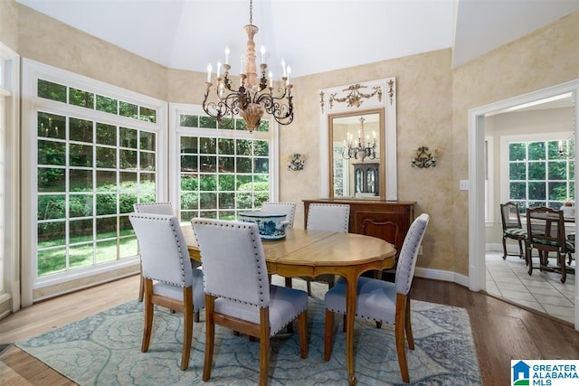 dining area with vaulted ceiling, wood-type flooring, and an inviting chandelier