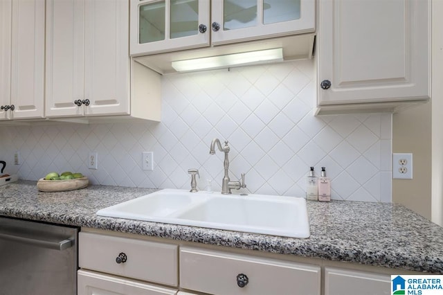 kitchen with decorative backsplash, sink, stainless steel dishwasher, and white cabinets