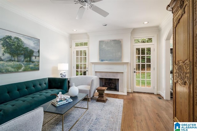 living room with light hardwood / wood-style floors, crown molding, and ceiling fan