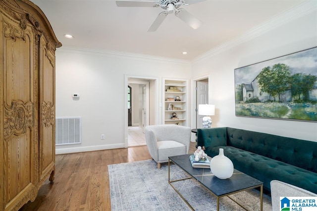 living room with crown molding, hardwood / wood-style flooring, built in shelves, and ceiling fan