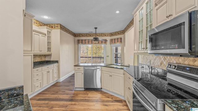 kitchen featuring appliances with stainless steel finishes, sink, cream cabinets, hanging light fixtures, and light hardwood / wood-style flooring