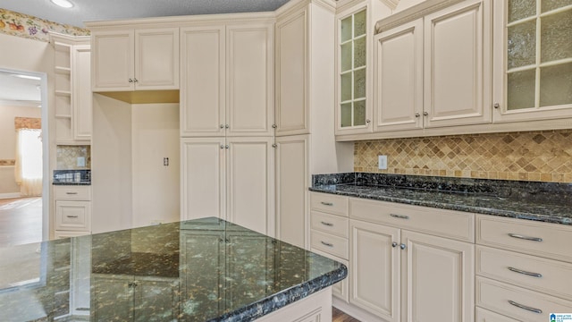 kitchen featuring tasteful backsplash, cream cabinets, and dark stone counters