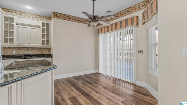 interior space with decorative backsplash, white cabinetry, dark wood-type flooring, and dark stone counters