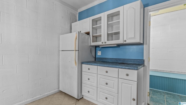 kitchen featuring crown molding, white cabinets, light tile patterned flooring, and white refrigerator