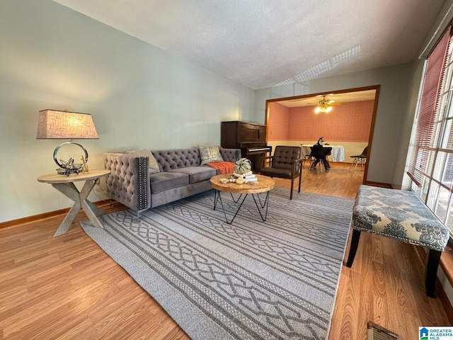 living room featuring a textured ceiling, light wood-type flooring, and lofted ceiling