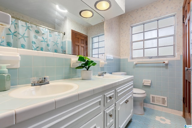 bathroom with tile walls, vanity, a shower with shower curtain, tile patterned flooring, and toilet