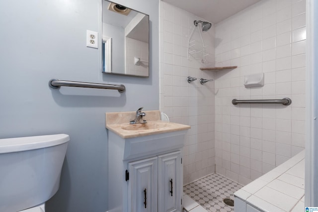 bathroom with vanity, toilet, and tiled shower