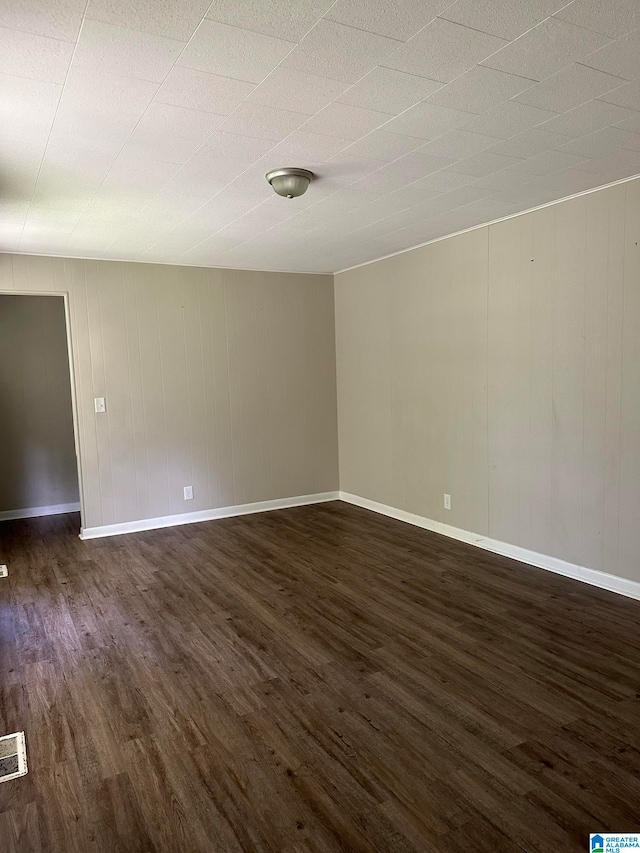 spare room featuring wooden walls and dark hardwood / wood-style floors