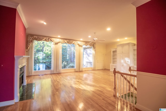 unfurnished living room with ceiling fan, a healthy amount of sunlight, light hardwood / wood-style flooring, and crown molding