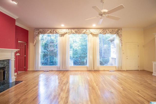 unfurnished living room featuring ceiling fan, light hardwood / wood-style floors, a healthy amount of sunlight, and a fireplace