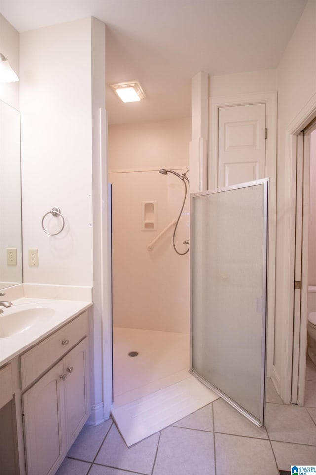 bathroom featuring walk in shower, toilet, vanity, and tile patterned floors