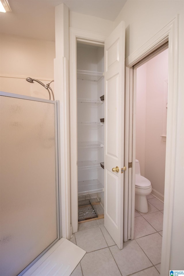 bathroom featuring walk in shower, tile patterned flooring, and toilet