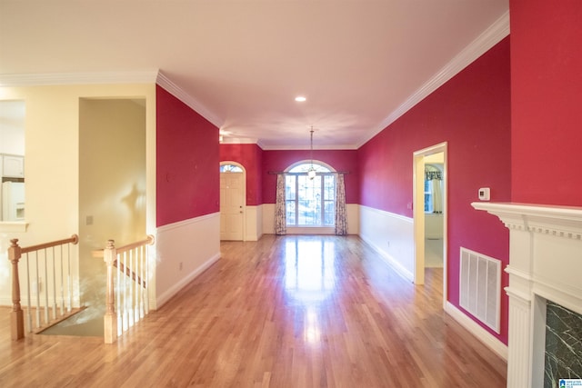 interior space with light hardwood / wood-style floors, a chandelier, a premium fireplace, and ornamental molding