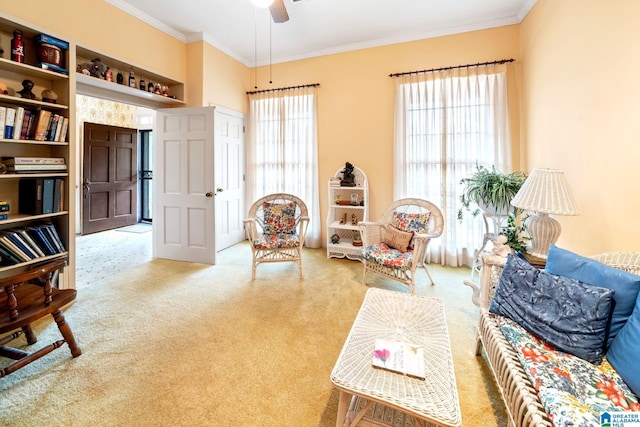 sitting room with ceiling fan, crown molding, and carpet