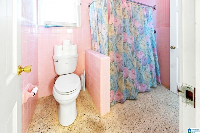 bathroom with a shower with shower curtain, toilet, and tile walls